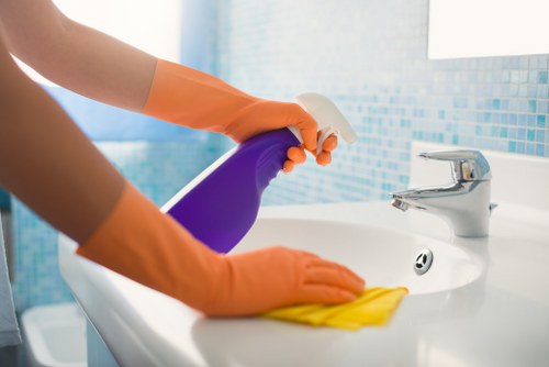 Employee using approved cleaning products with proper safety precautions