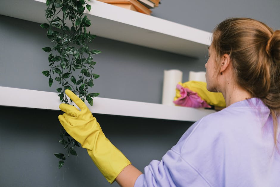A person wearing a beige shirt is placing a cleaning cloth onto a white, glossy surface, possibly a cabinet or a appliance. The surface appears clean and reflective with no visible dust or smudges. In